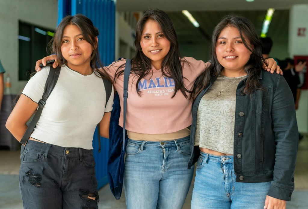 three young women standing together in a hallway