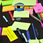 Colorful assortment of office supplies on a desk, including sticky notes, pens, and markers.