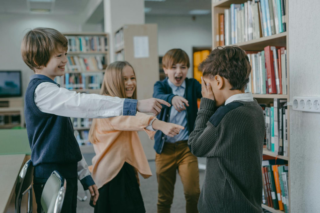 a group of children laughing at a boy in a library