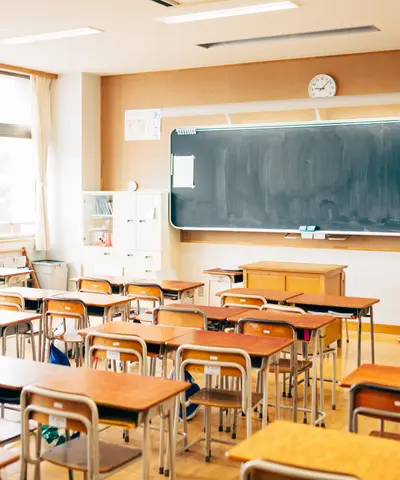 Several desks are arranged in neat rows. The room is bright and sunny, showing a classroom under control