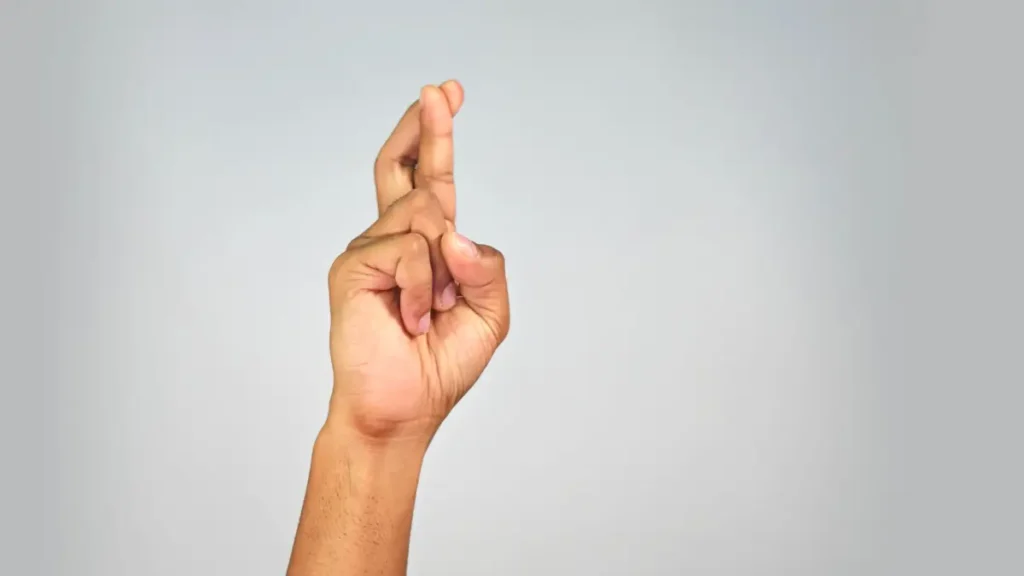 A student's hand is raised with crossed fingers, showing a clear bathroom signal for classrooms in upper elementary grades