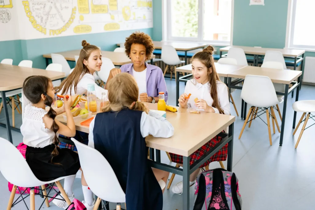 A group of fifth grade students sit together and have a class meeting while they eat their lunch
