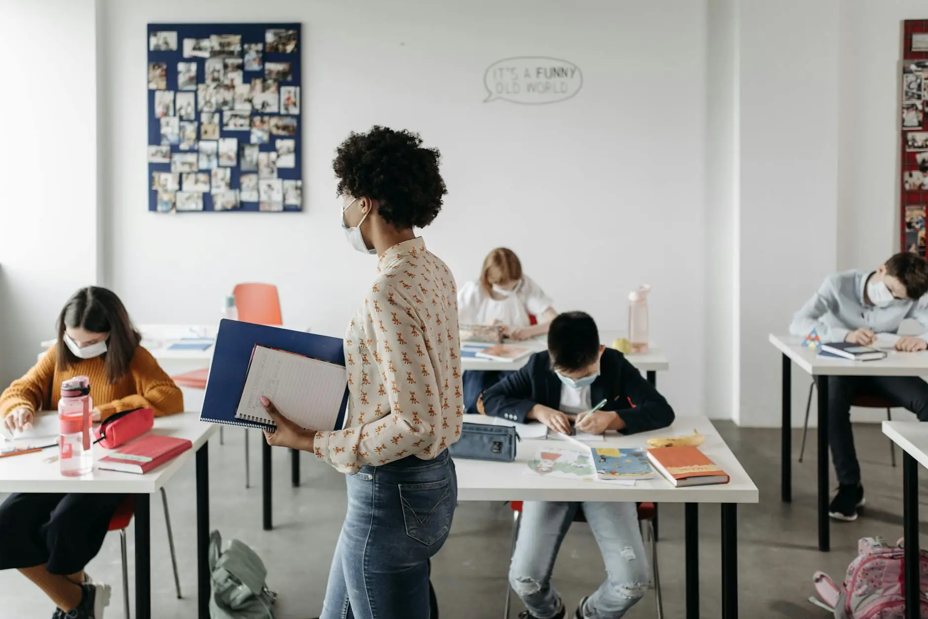A teacher walks across the front of the room as her middle school students work on time-filler activities at their desks
