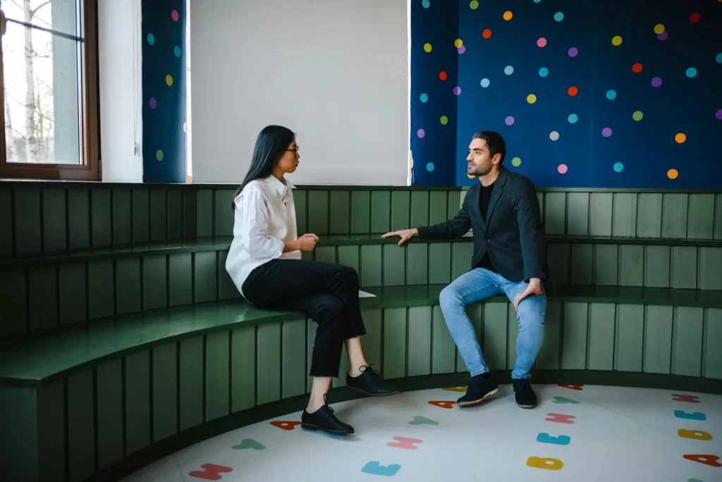 A teacher and a parent have a pleasant conversation inside a classroom