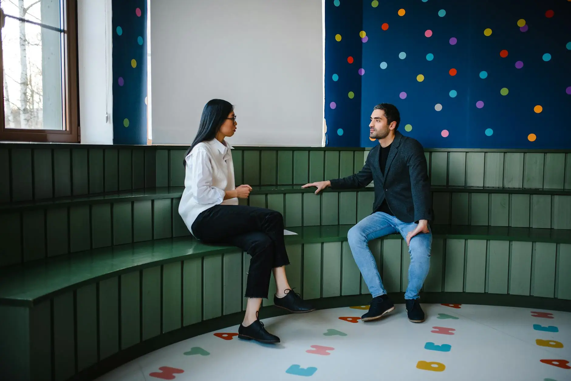 A teacher and a parent have a pleasant conversation inside a classroom