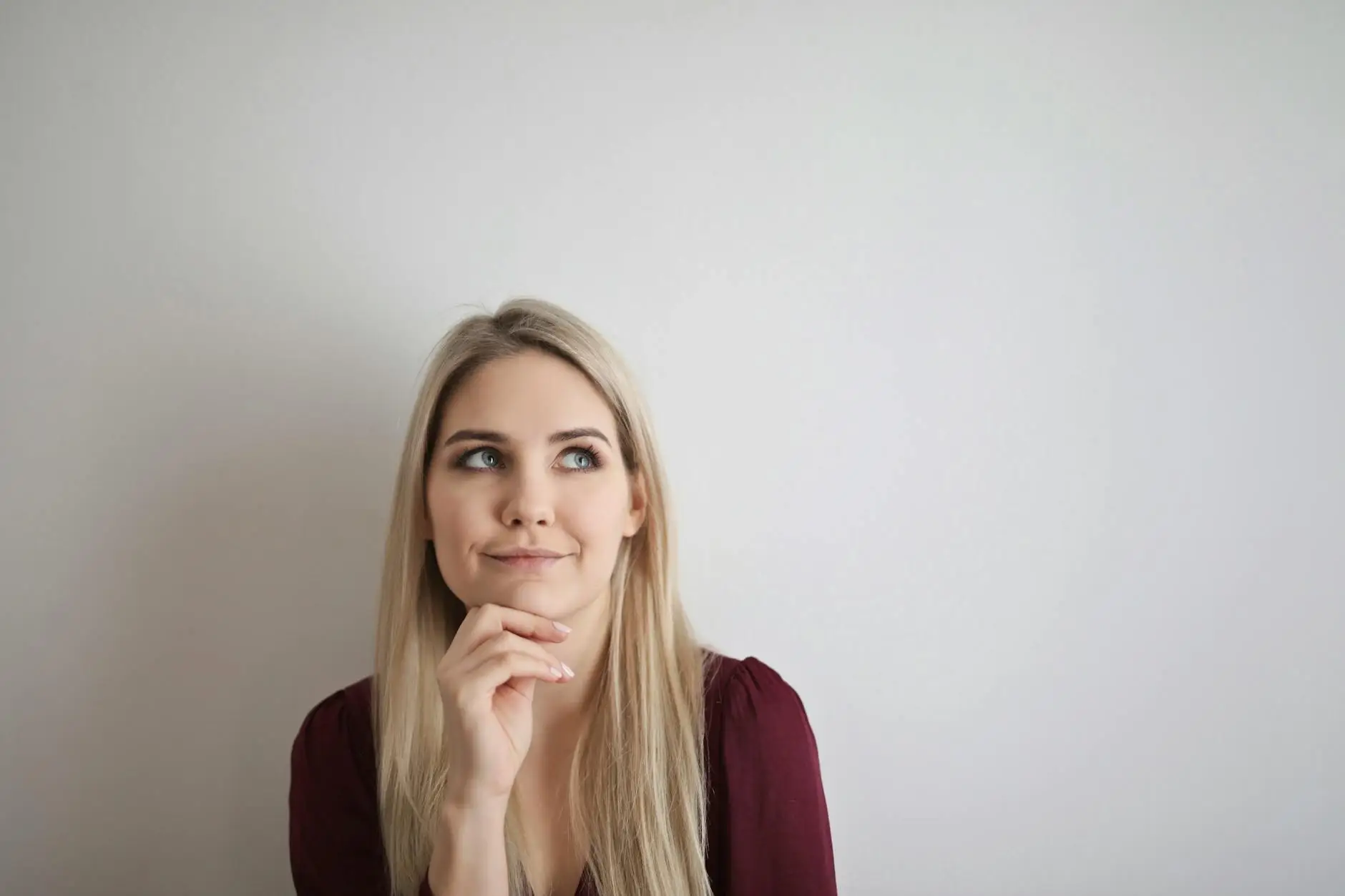 A blonde woman in a red top rests her chin lightly on her hand as she thinks about the quiet signal that would work best for her teaching style and her students