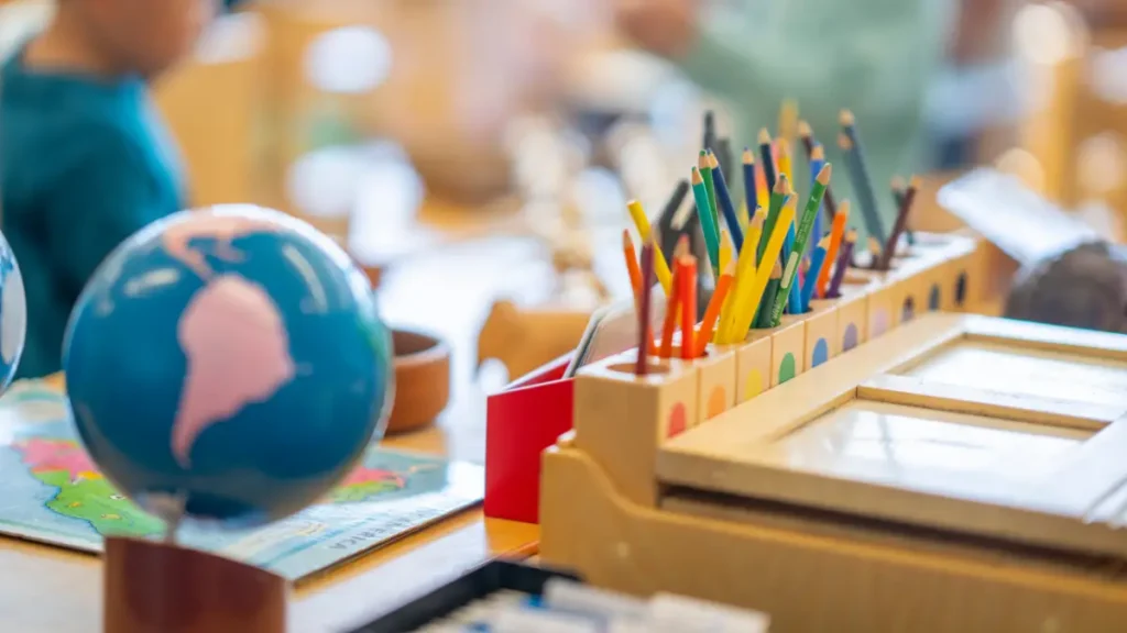 A classroom setup with bright colors and an organized desk including a globe and colored pencils arranged by color